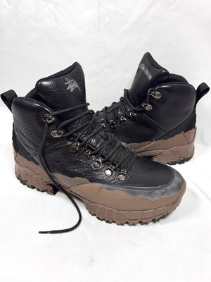 Pair of Stüssy x ROA Andreas hiking boots in Black and Mud on a white background