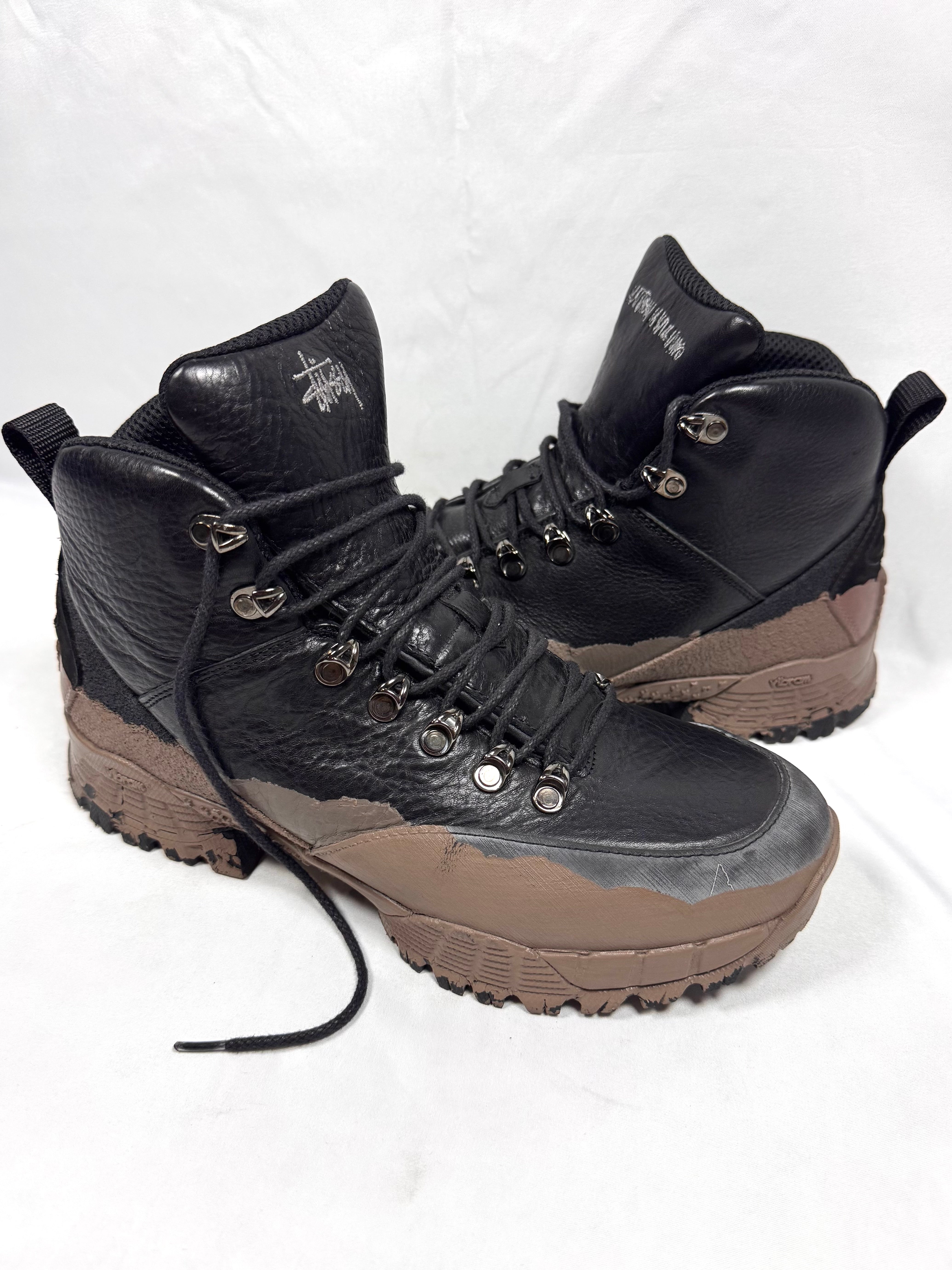 Pair of Stüssy x ROA Andreas hiking boots in Black and Mud on a white background