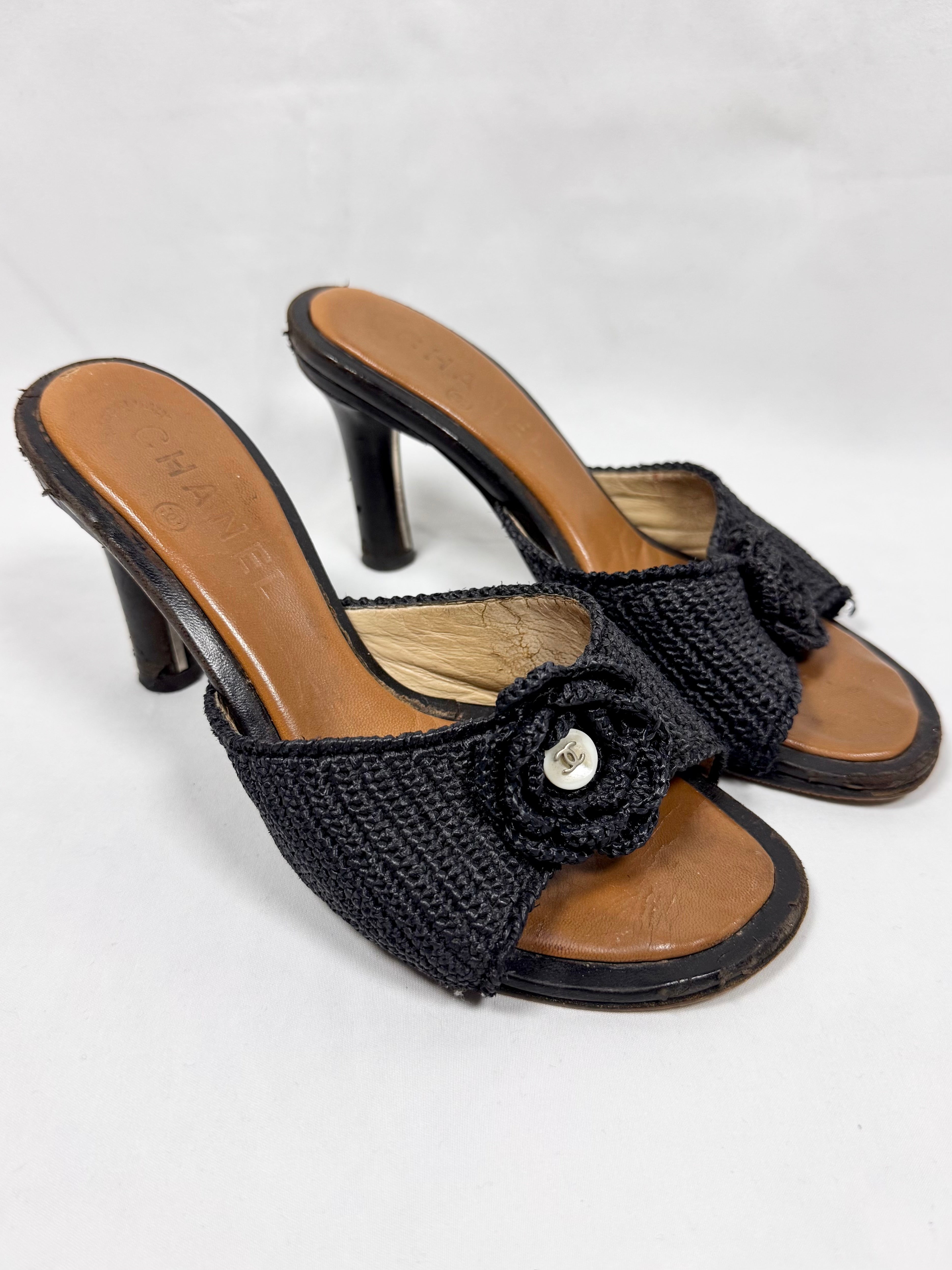 Pair of vintage Chanel black raffia mule heels with camellia flower detail on white background 
