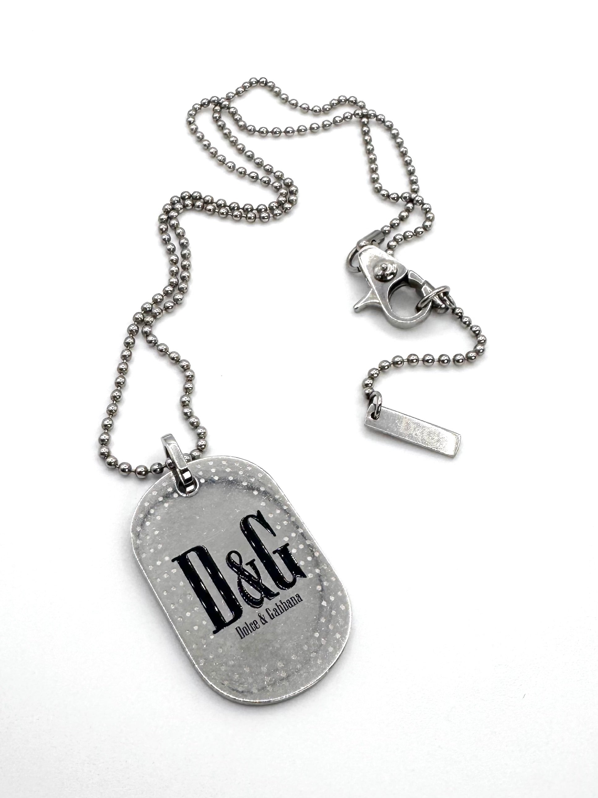 Vintage 2000s Dolce & Gabbana D&G logo dog tag necklace with silver-tone speckled pendant, ball chain, and branded lobster clasp on white background.