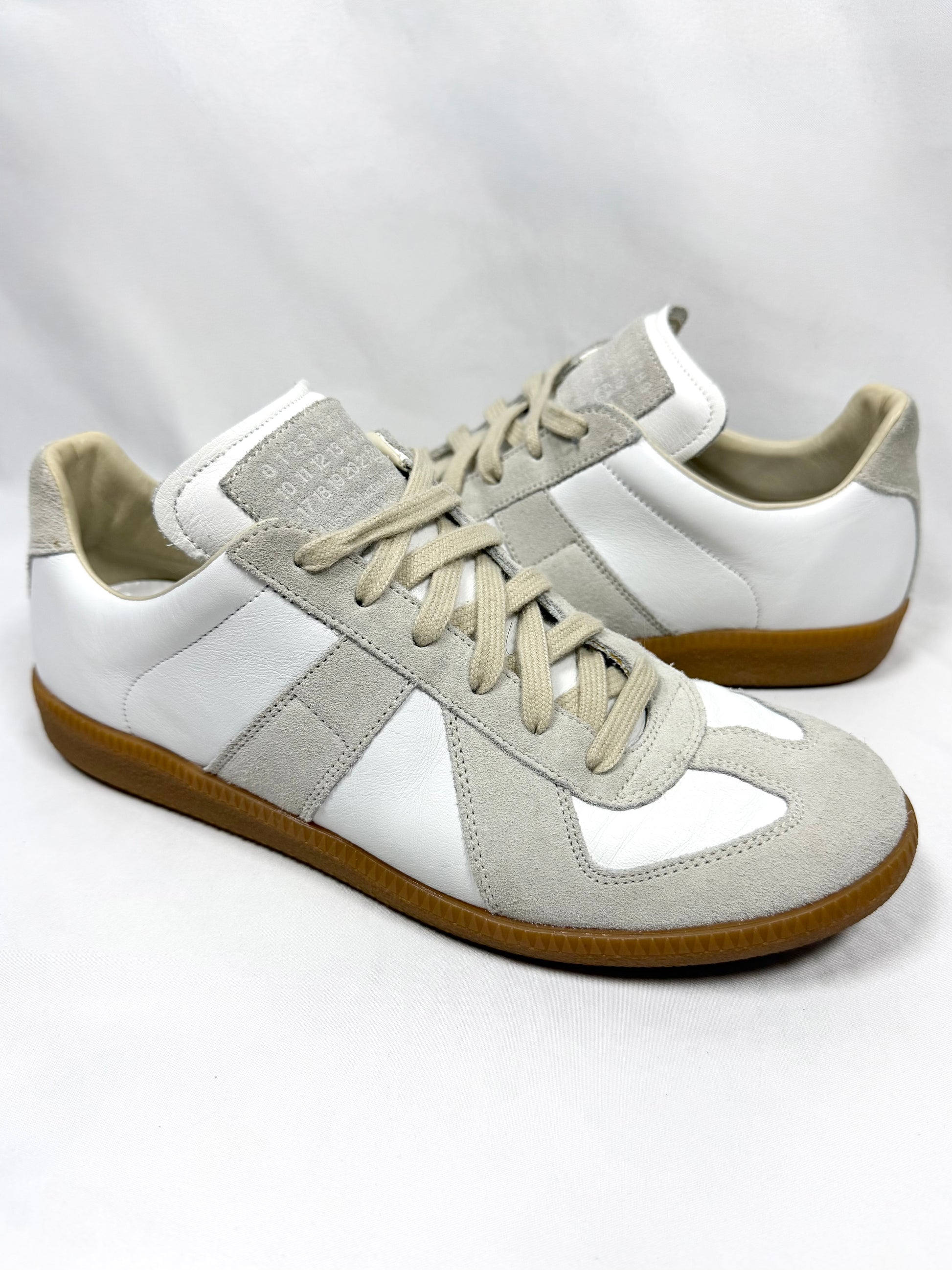 Pair of white and gray Maison Margiela German army trainers with brown soles on a white background