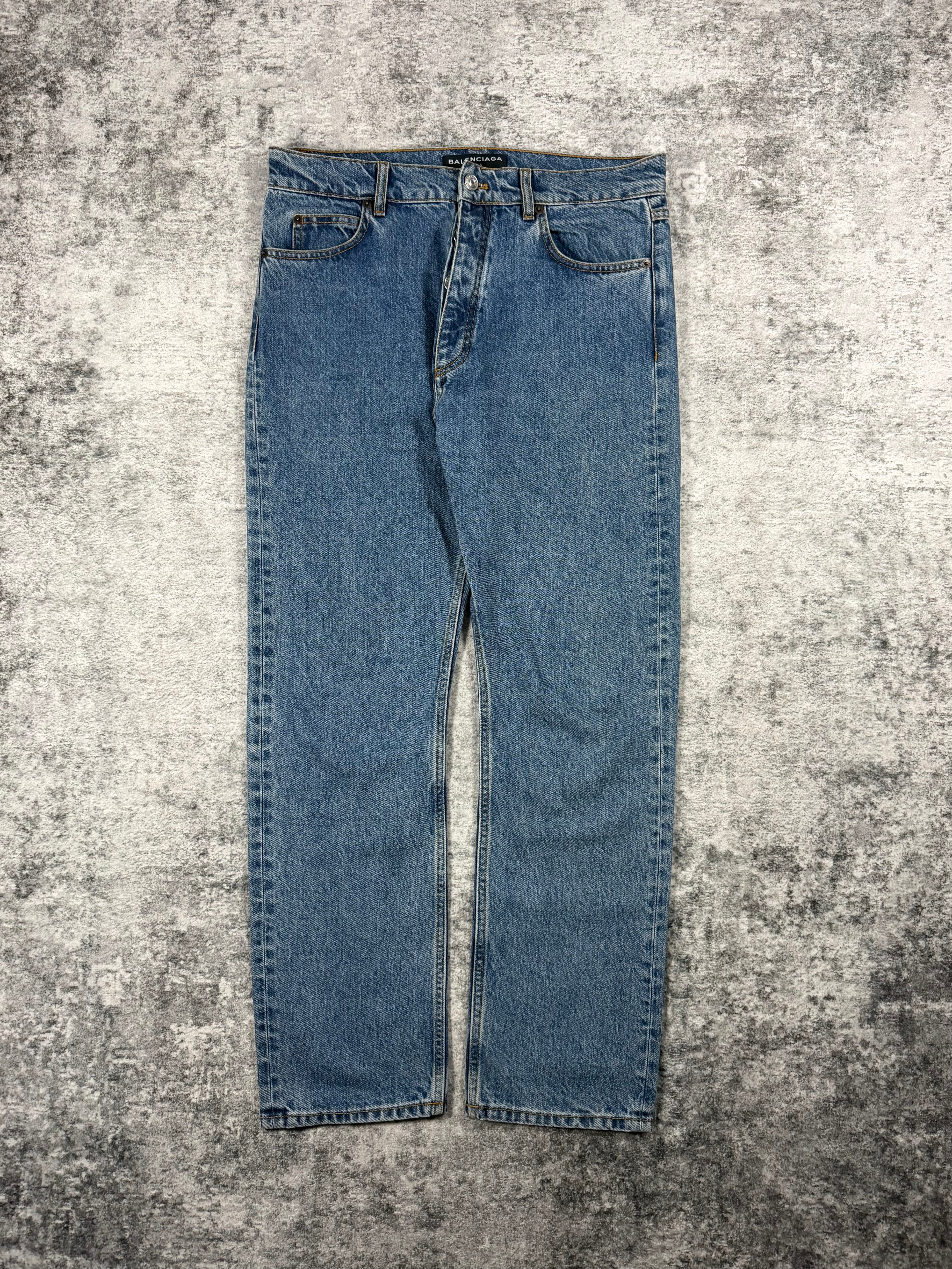 Pair of blue Balenciaga jeans on a textured gray surface