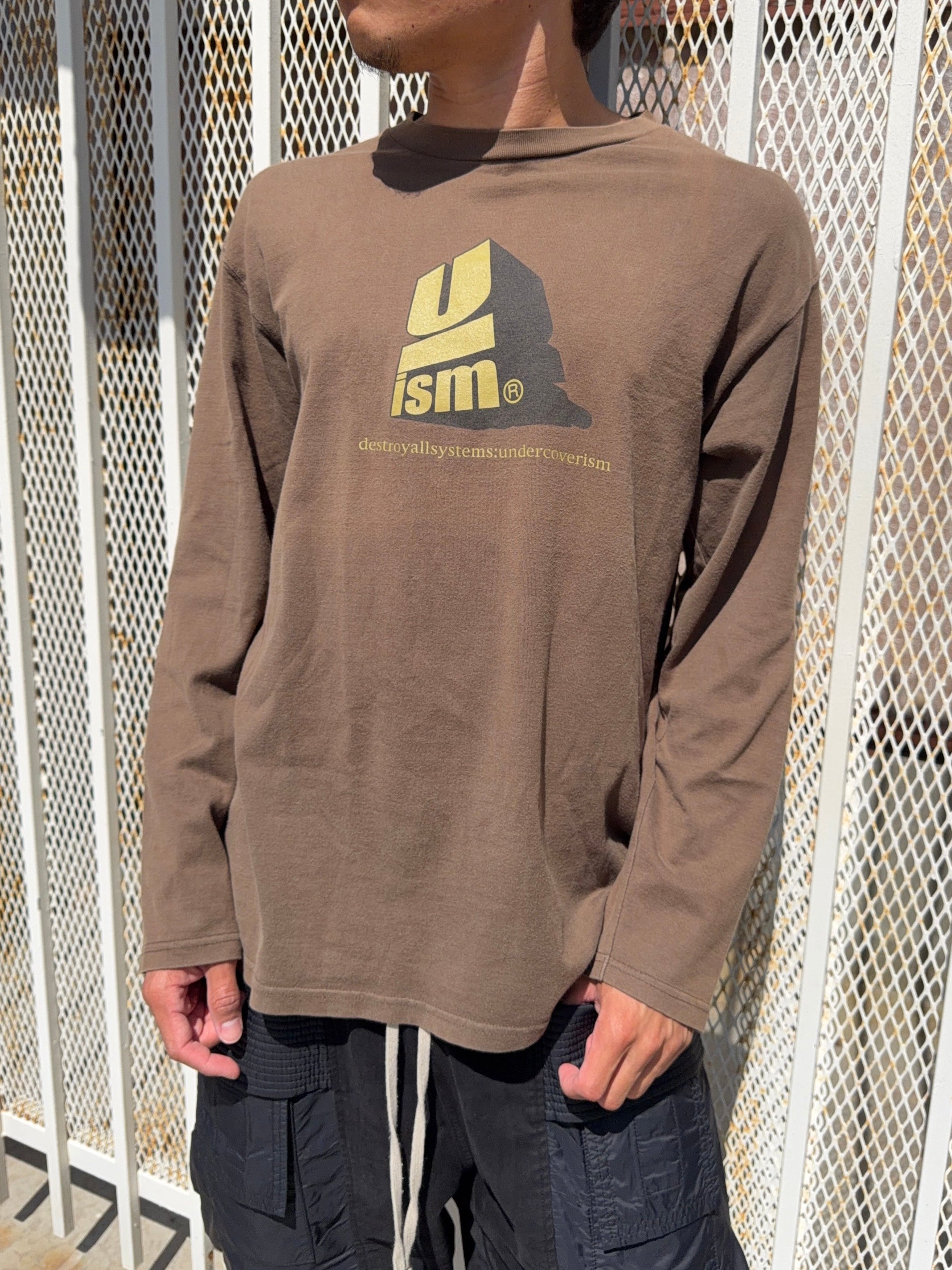 Model wearing brown undercover longsleeve from Autumn/Winter 2000 with ‘Uism’ rebel message graphic.