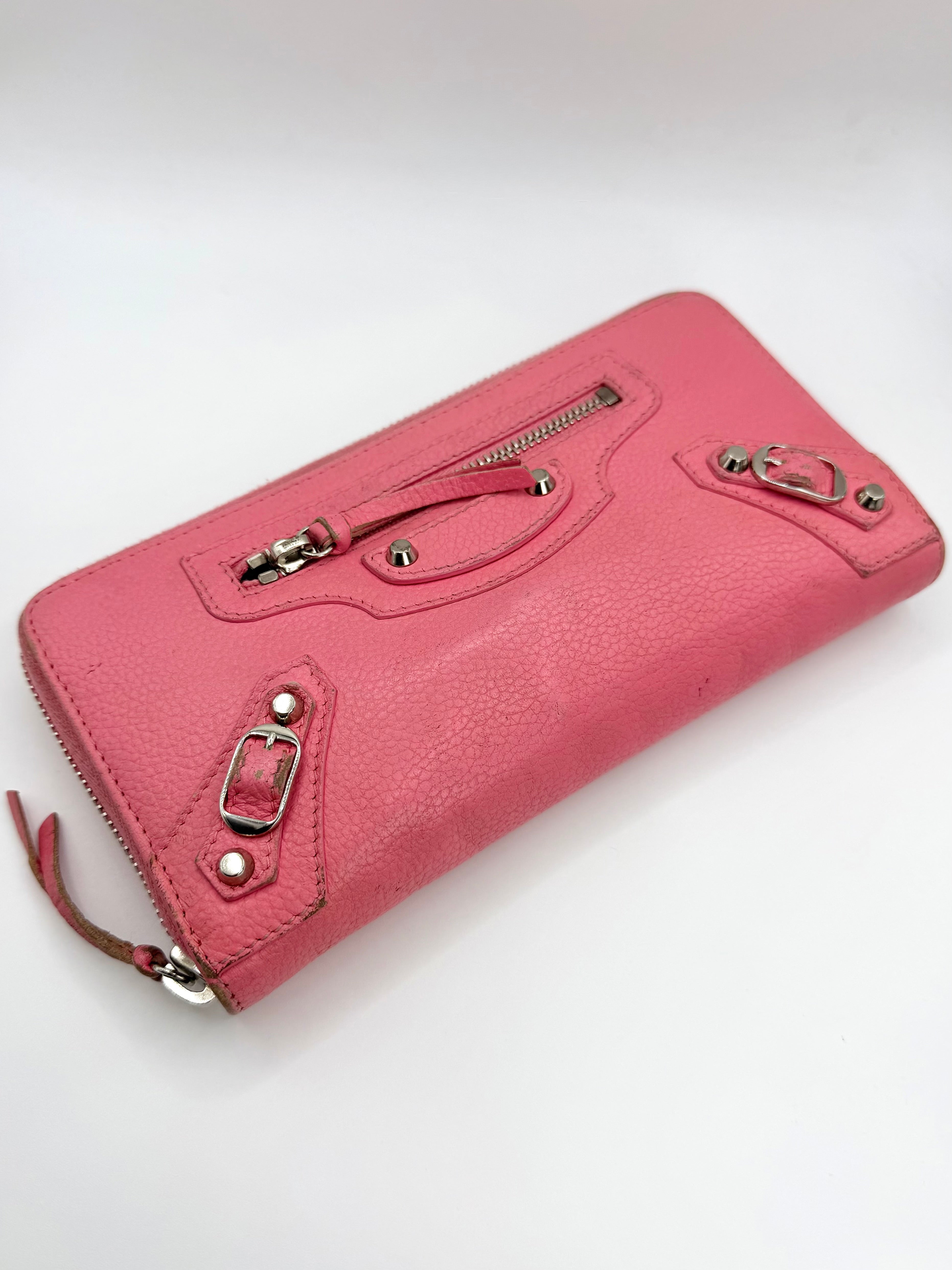 Pink Balenciaga wallet with silver zippers on a white background