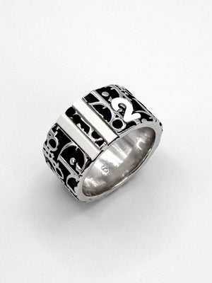 Close-up of Christian Dior Trotter monogram wide band ring with black enamel logo pattern on silver-tone metal.