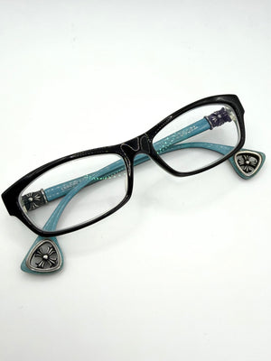 Black chrome hearts d Sanchez cat-eye eyeglasses with turquoise blue temples featuring silver-tone decorative metal crosses and cut-out cross temple tips, shown on a plain white background.
