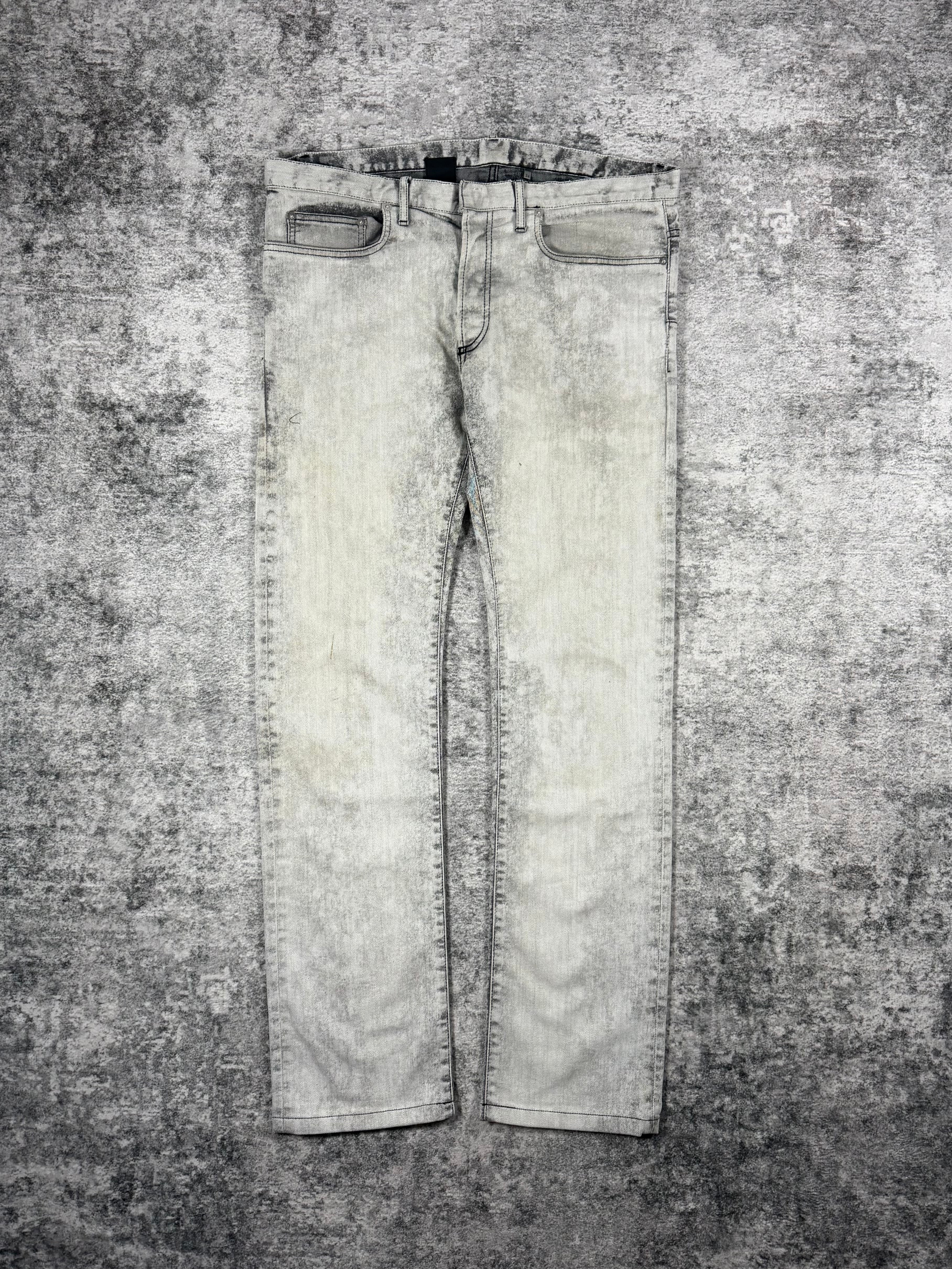 Pair of grey marble tone Dior Homme jeans designed by Kris Van Assche laid on a textured gray background