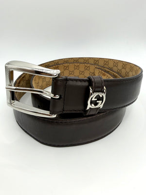 Black Gucci leather belt with a monogram interior and silver buckle with mini GG logo on a white background
