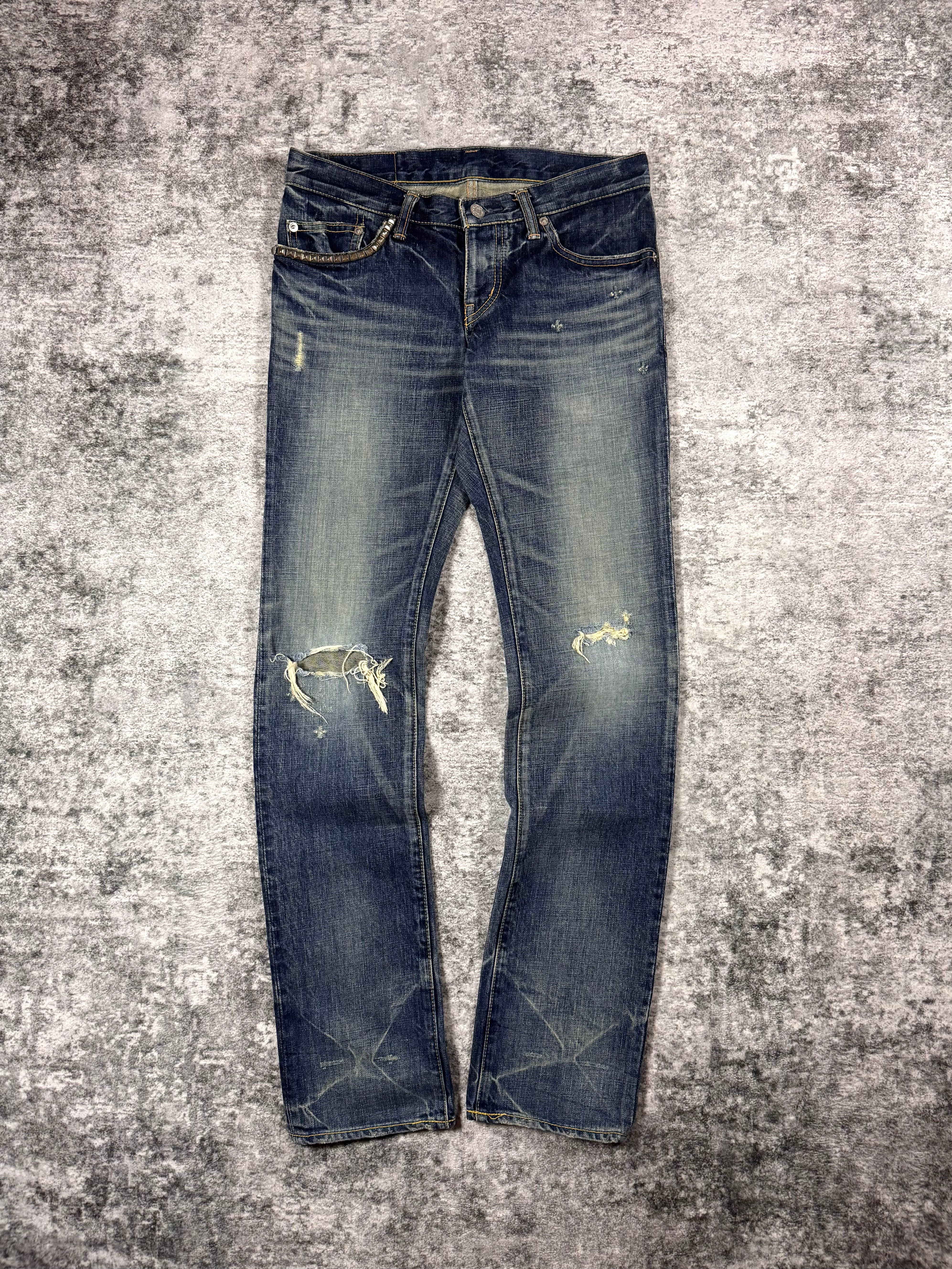 Hysteric Glamour studded pocket distressed indigo denim jeans front view on textured grey surface 