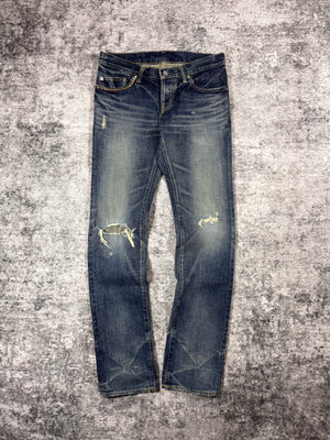 Hysteric Glamour studded pocket distressed indigo denim jeans front view on textured grey surface 