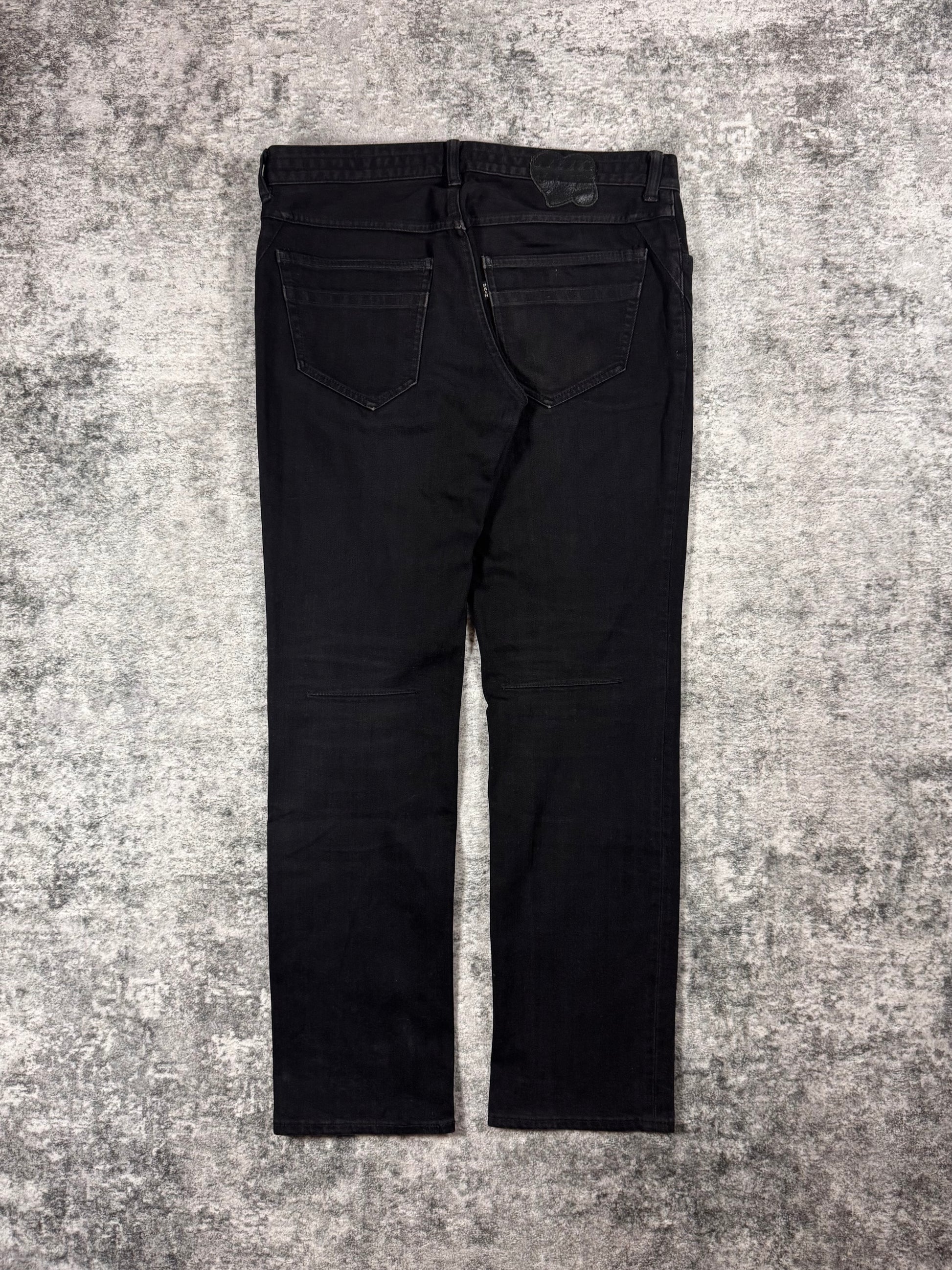 Black Number (N)ine jeans from SS2007 “About A Boy” on a textured gray surface