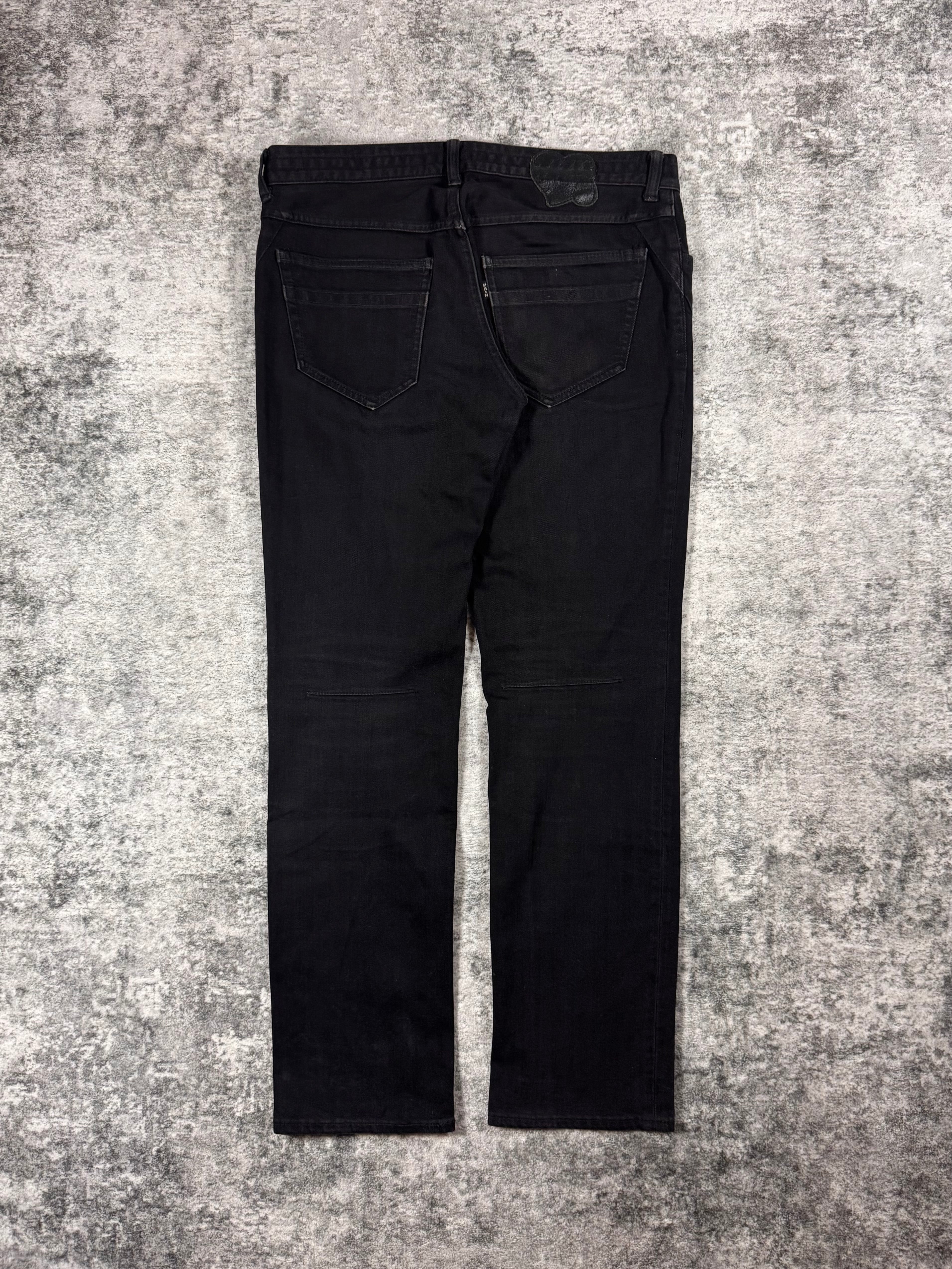 Black Number (N)ine jeans from SS2007 “About A Boy” on a textured gray surface
