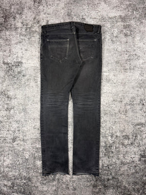 Number Nine denim from Spring Summer 2007 with intentional mud wash effect on the denim with darted thighs, as well as the signature crying heart patch showcased on the rear. Showcased on grey background.