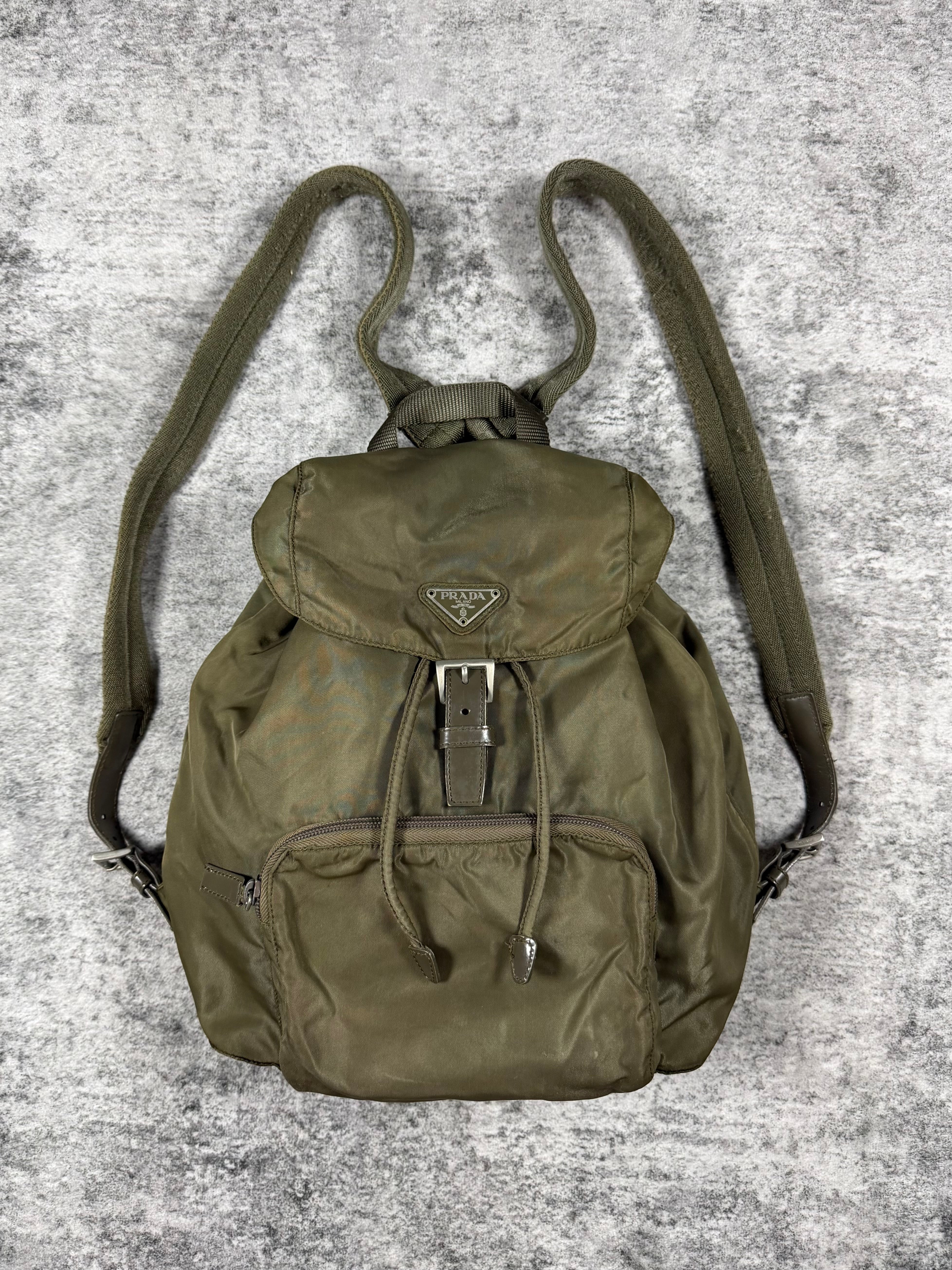 military green Prada backpack on a textured gray background