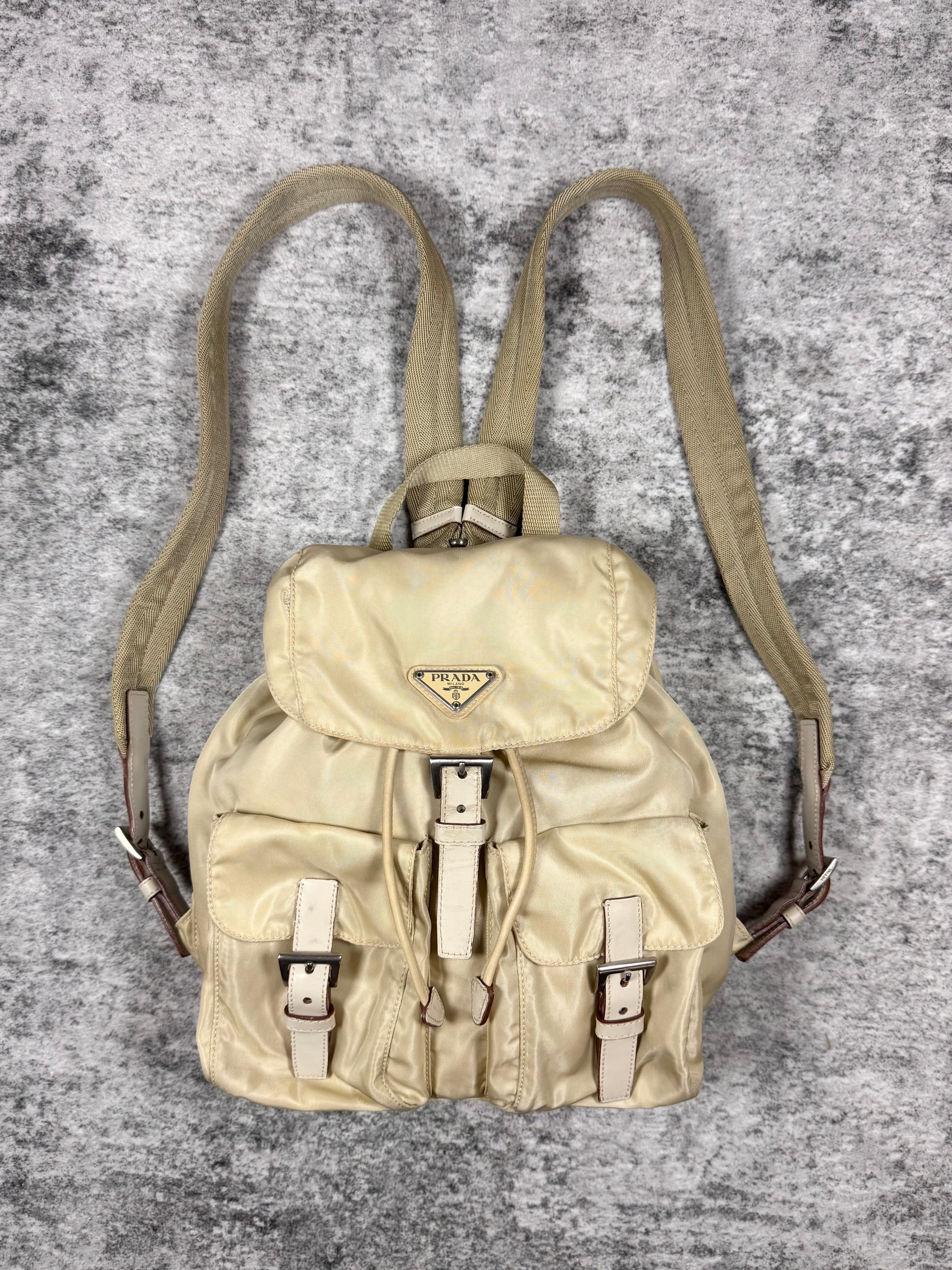Vintage creams backpack with leather straps on a textured gray background