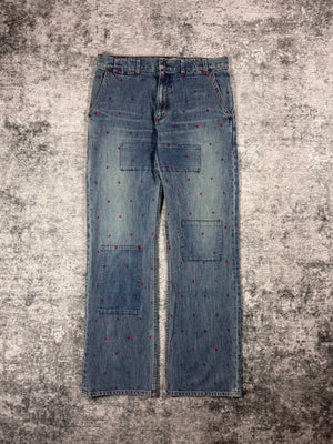 Undercover denim from
SS02 designed by Jun Takahashi with micro-red diamond shaped embroidered scattered throughout, laid out on a grey background 