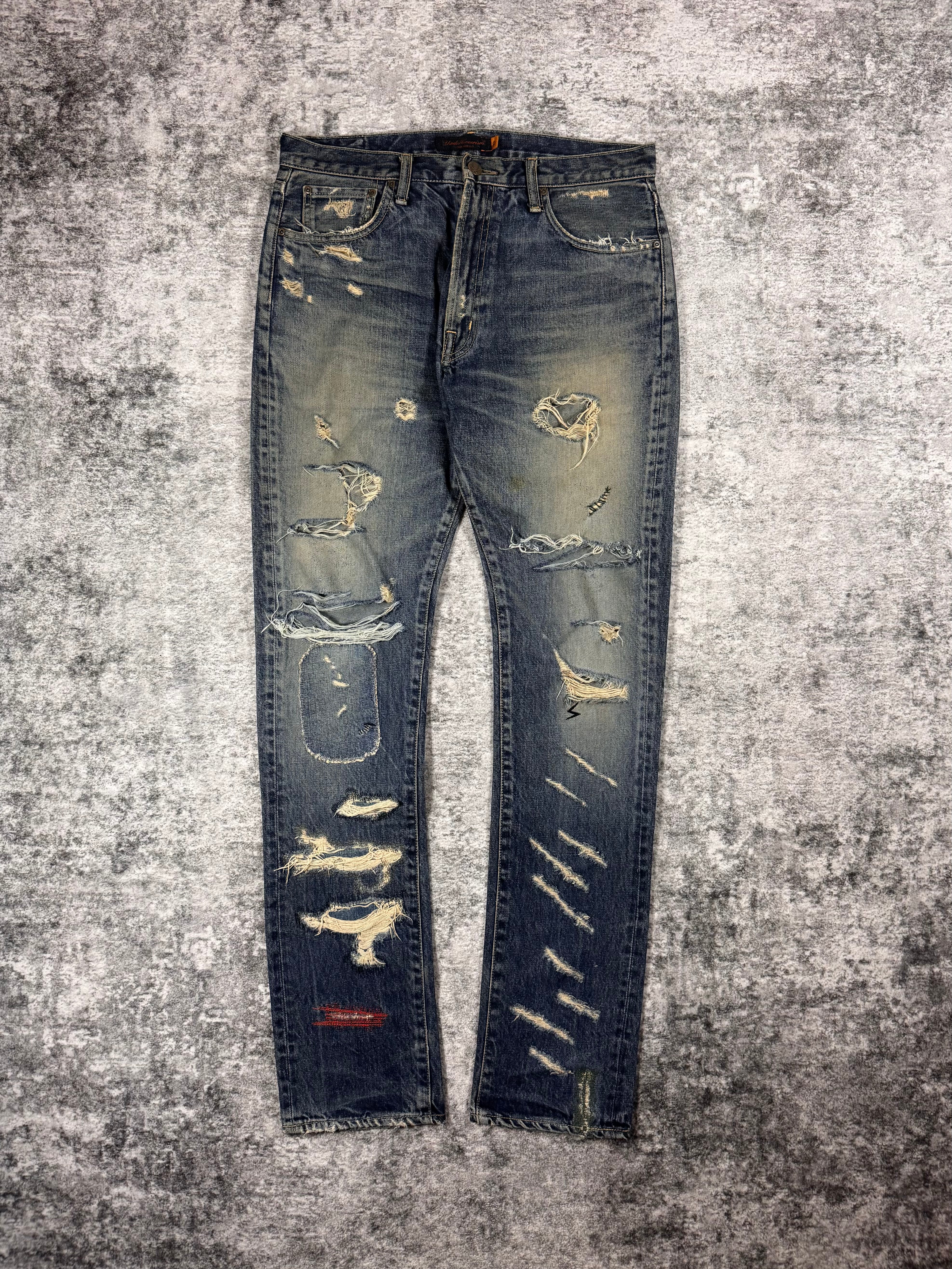 Front view of SS05 Undercover “But Beautiful” distressed patchwork denim jeans with heavy repair detailing and natural thrashing from wear — designed by Jun Takahashi 
