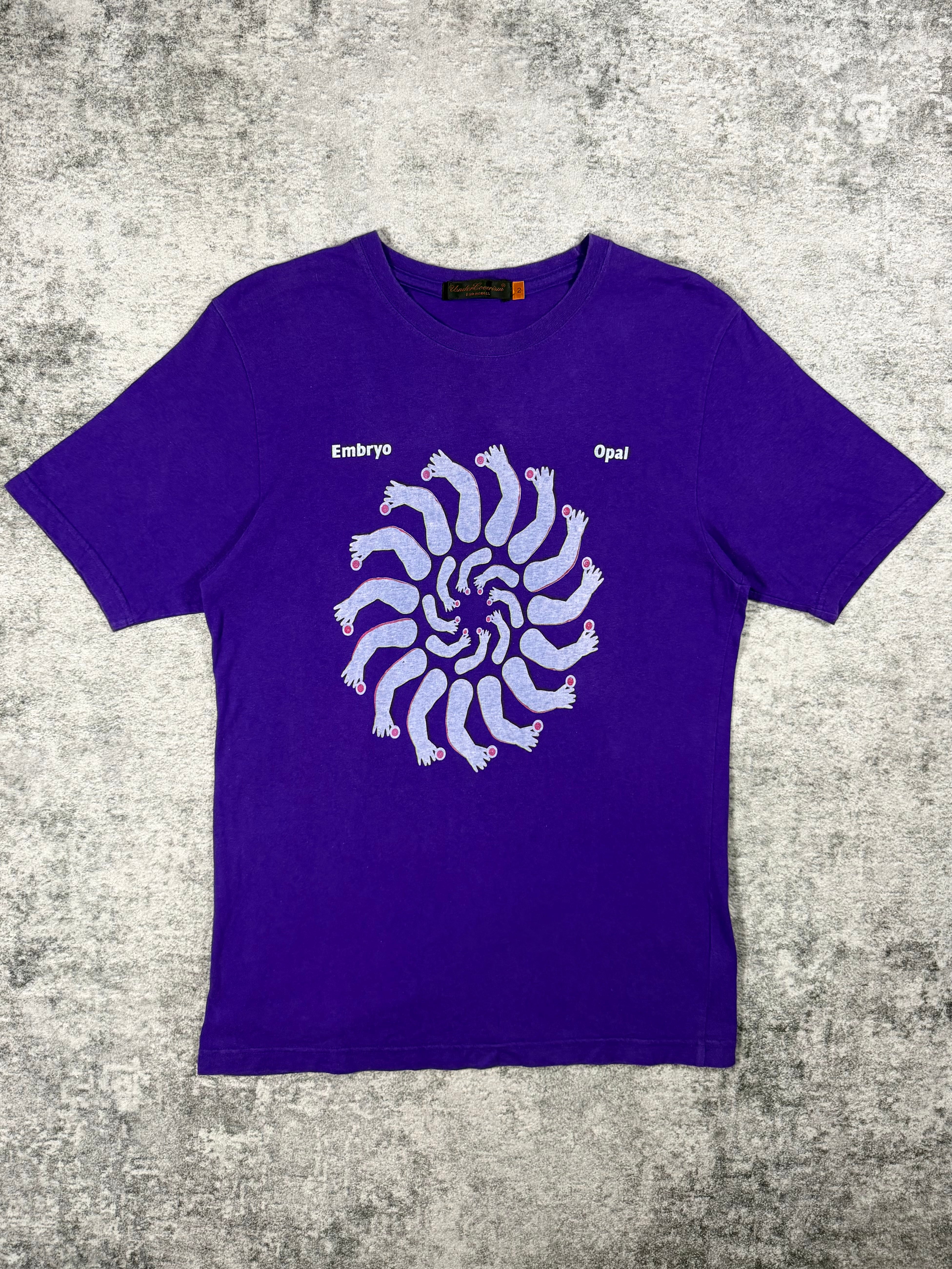 A purple Undercover short-sleeve t-shirt from 2006 inspired by German rock with a white spiral foot graphic and the words 'Embryo Opal' directly referencing the album released in 1970.