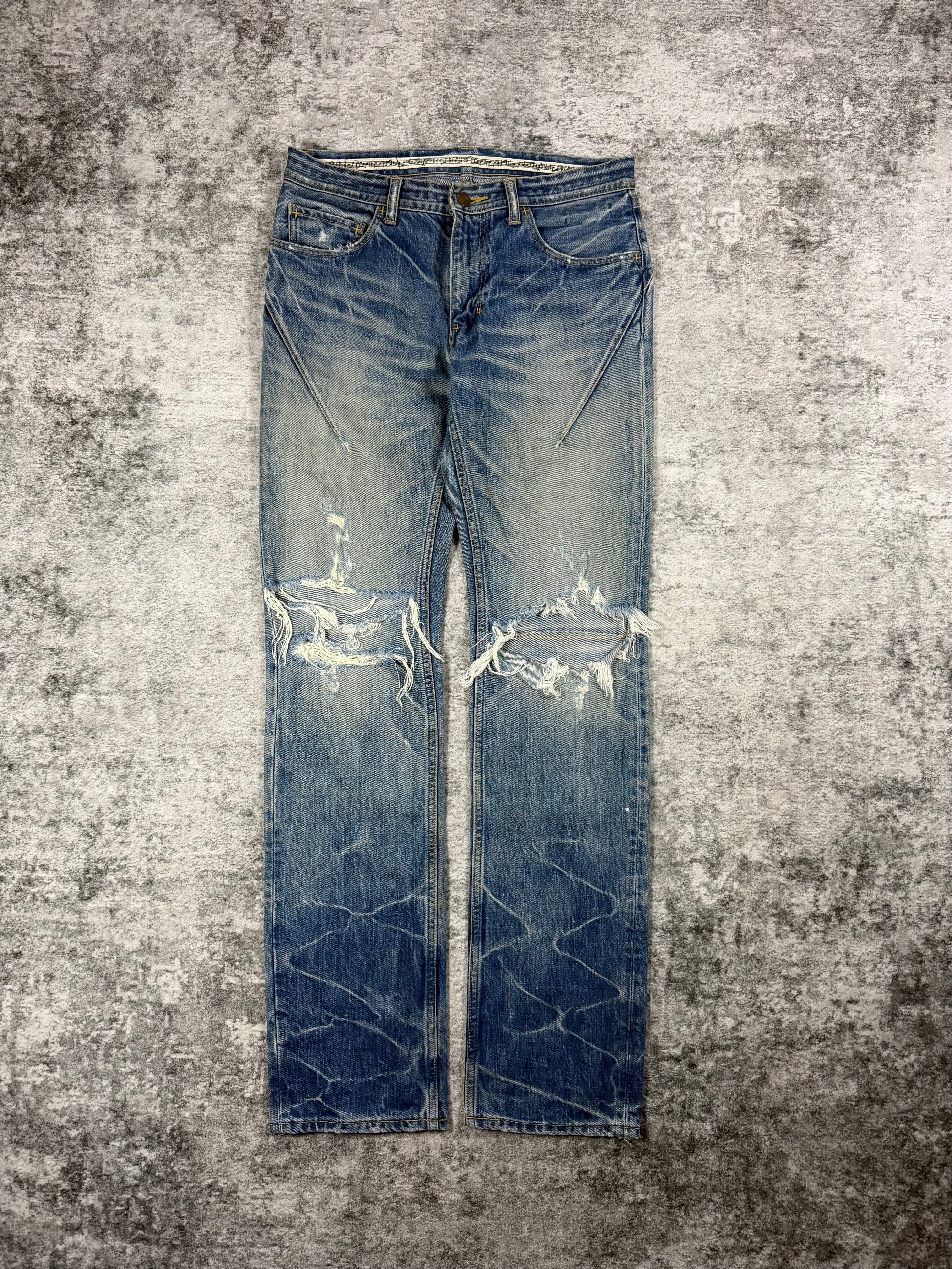 Distressed Number (N)ine faded blue pain denim jeans with honeycomb detail and natural distressing on a textured gray background
