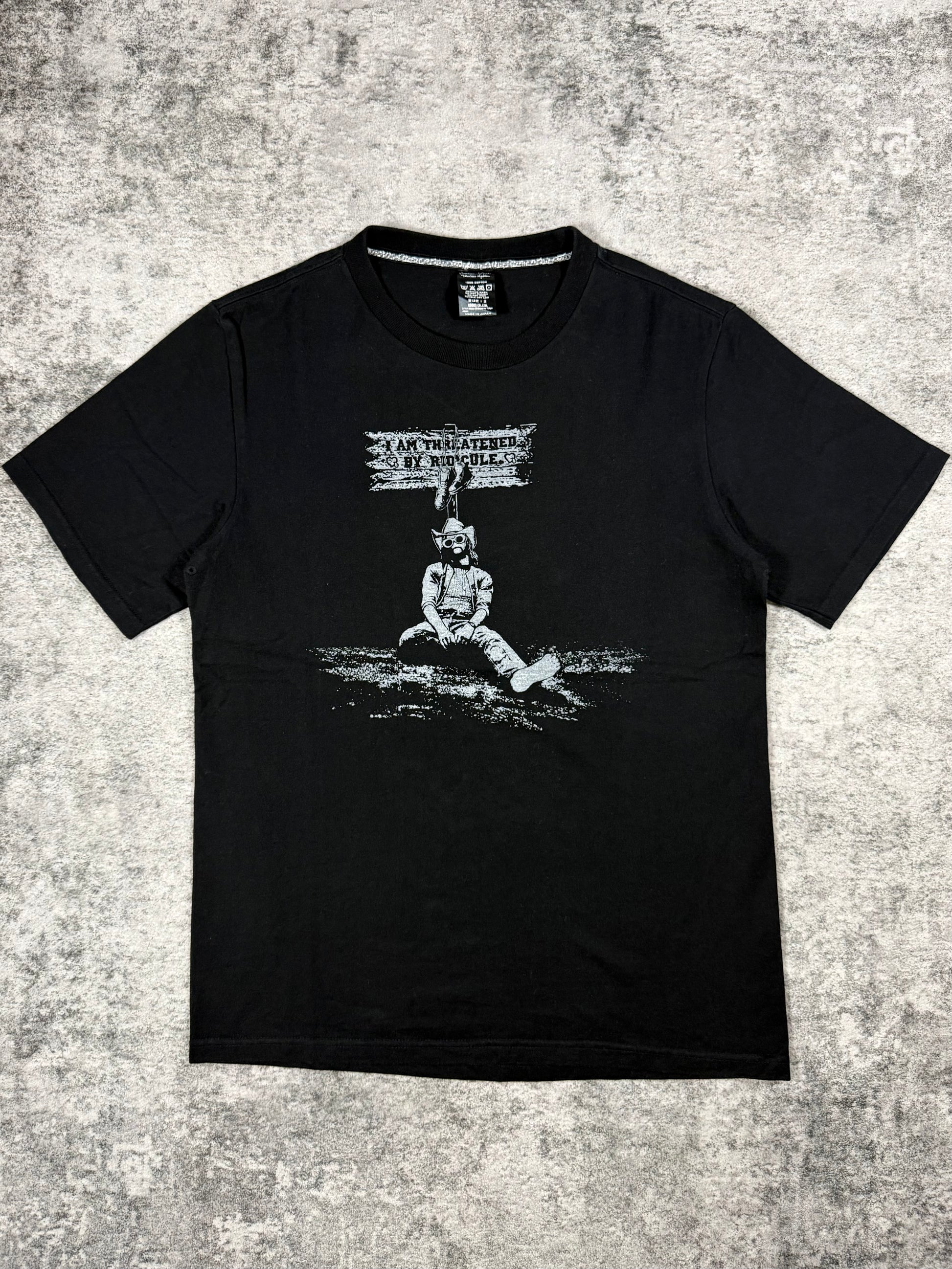 SS07 Number (N)ine “Threatened By Ridicule” Kurt Cobain black graphic T-shirt from the About A Boy collection featuring monochrome portrait print and text graphic on front.