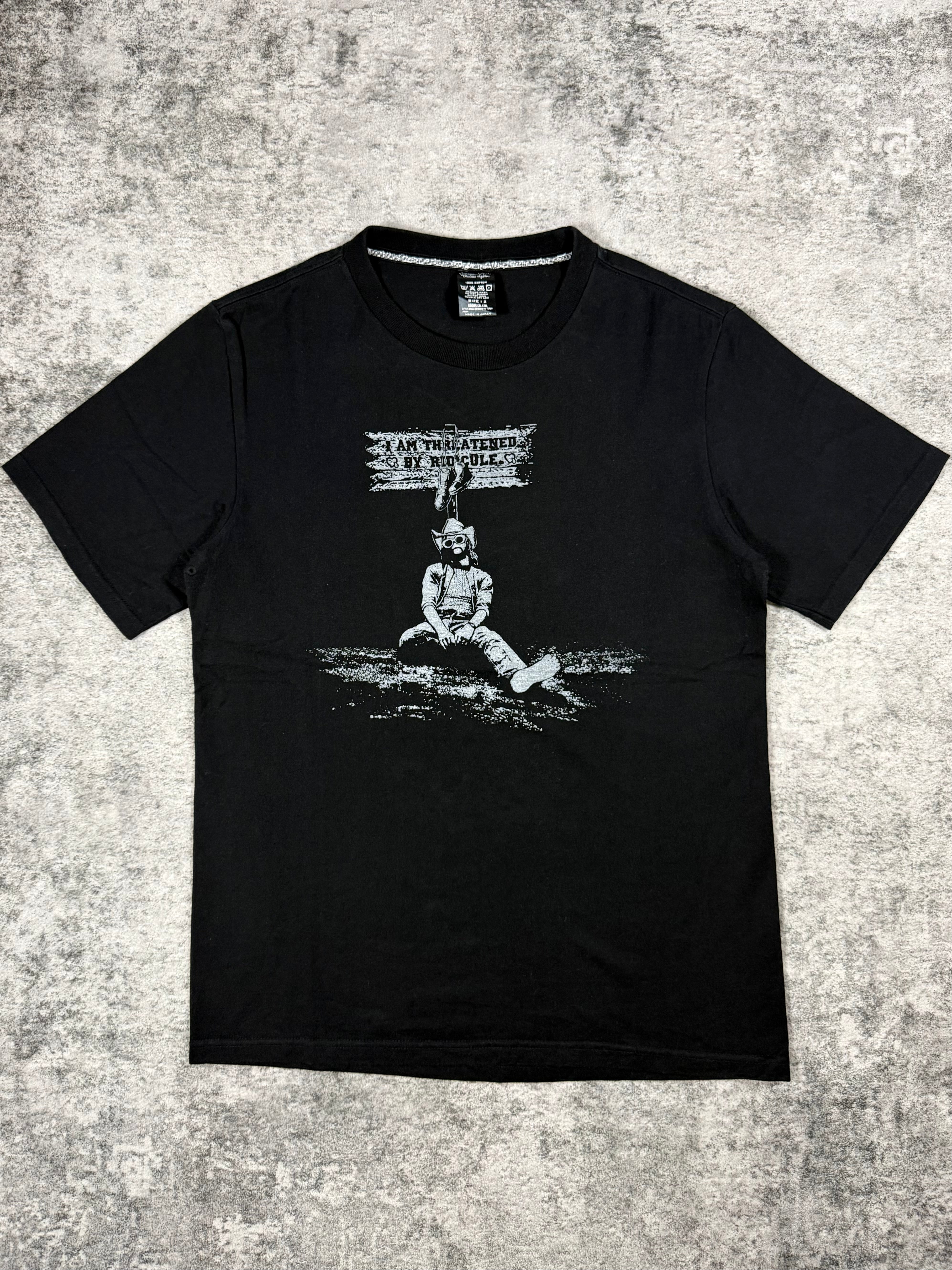 SS07 Number (N)ine “Threatened By Ridicule” Kurt Cobain black graphic T-shirt from the About A Boy collection featuring monochrome portrait print and text graphic on front.
