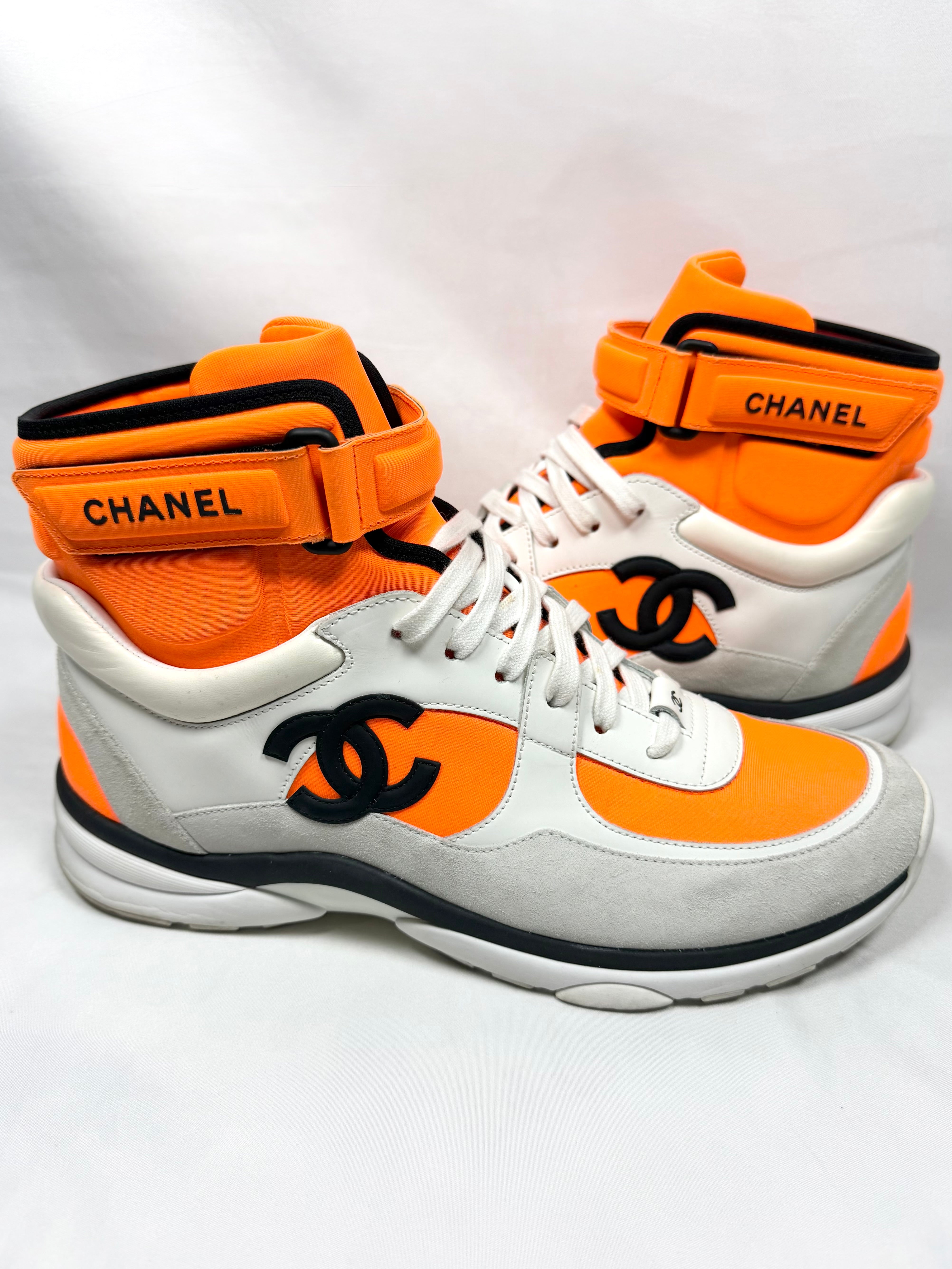 Orange and white Chanel sneakers with black CC logo on a white background