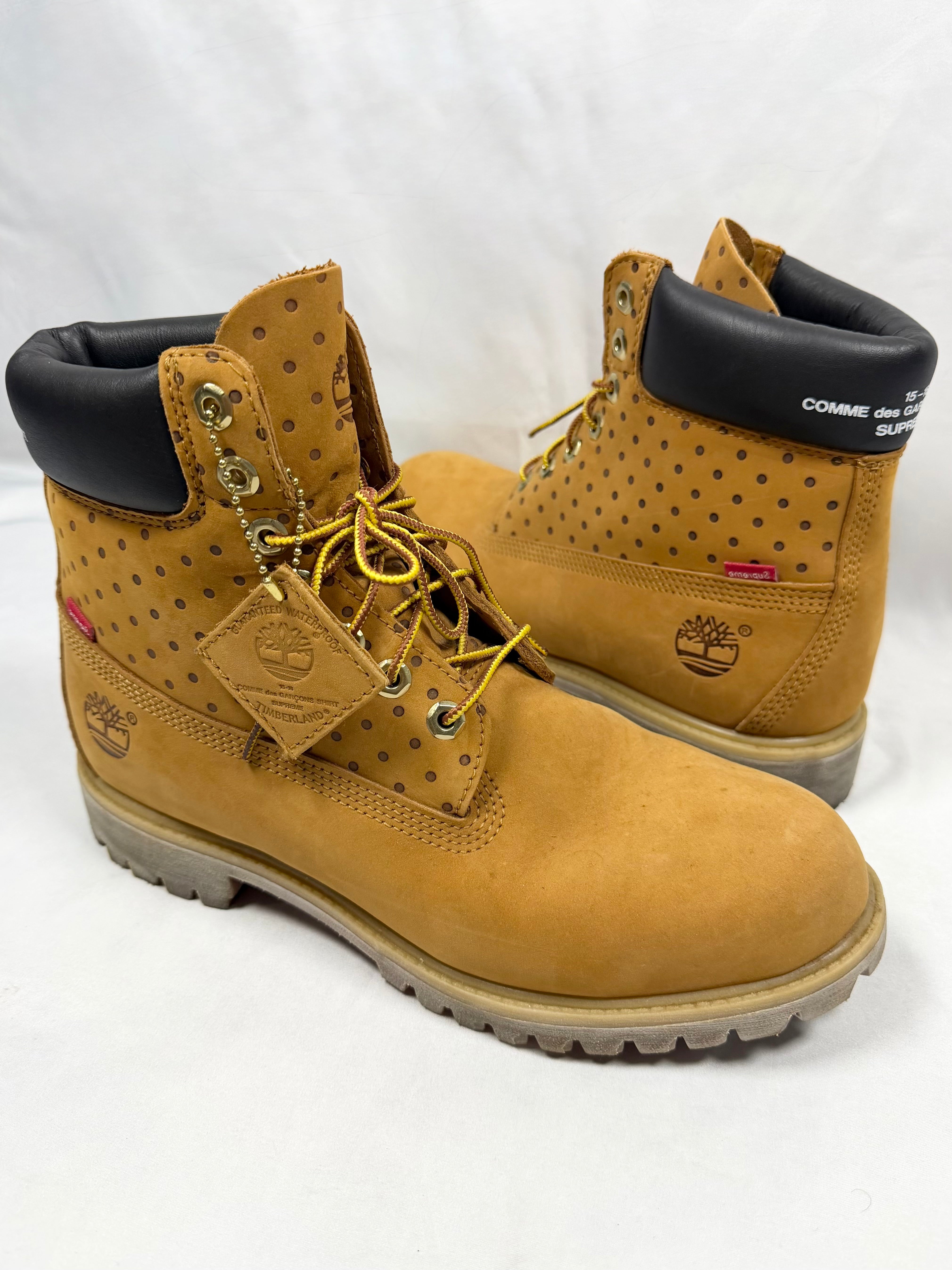 FW15 Supreme x Comme des Garçons SHIRT x Timberland wheat nubuck 6-inch boots with perforated polka dot detailing, co-branded black padded collars, red Supreme tab accents on white background. 