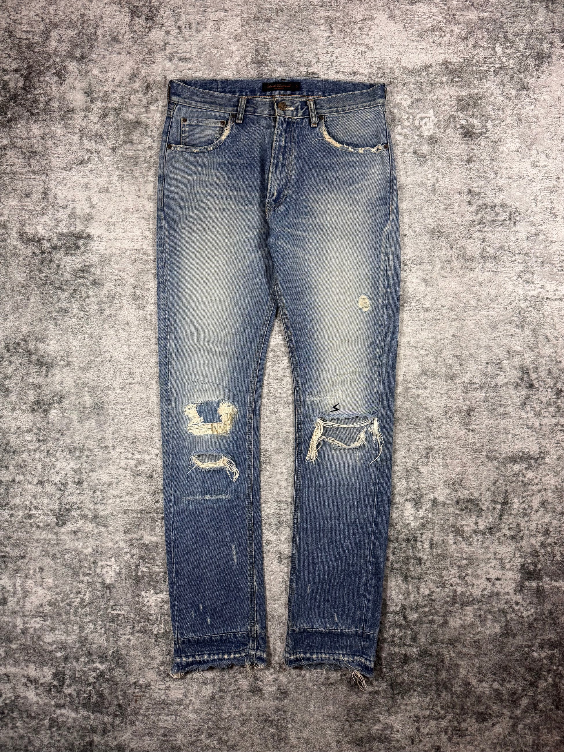 Undercover AW04 But Beautiful distressed indigo denim jeans with repaired knee distressing and vintage fading front view 