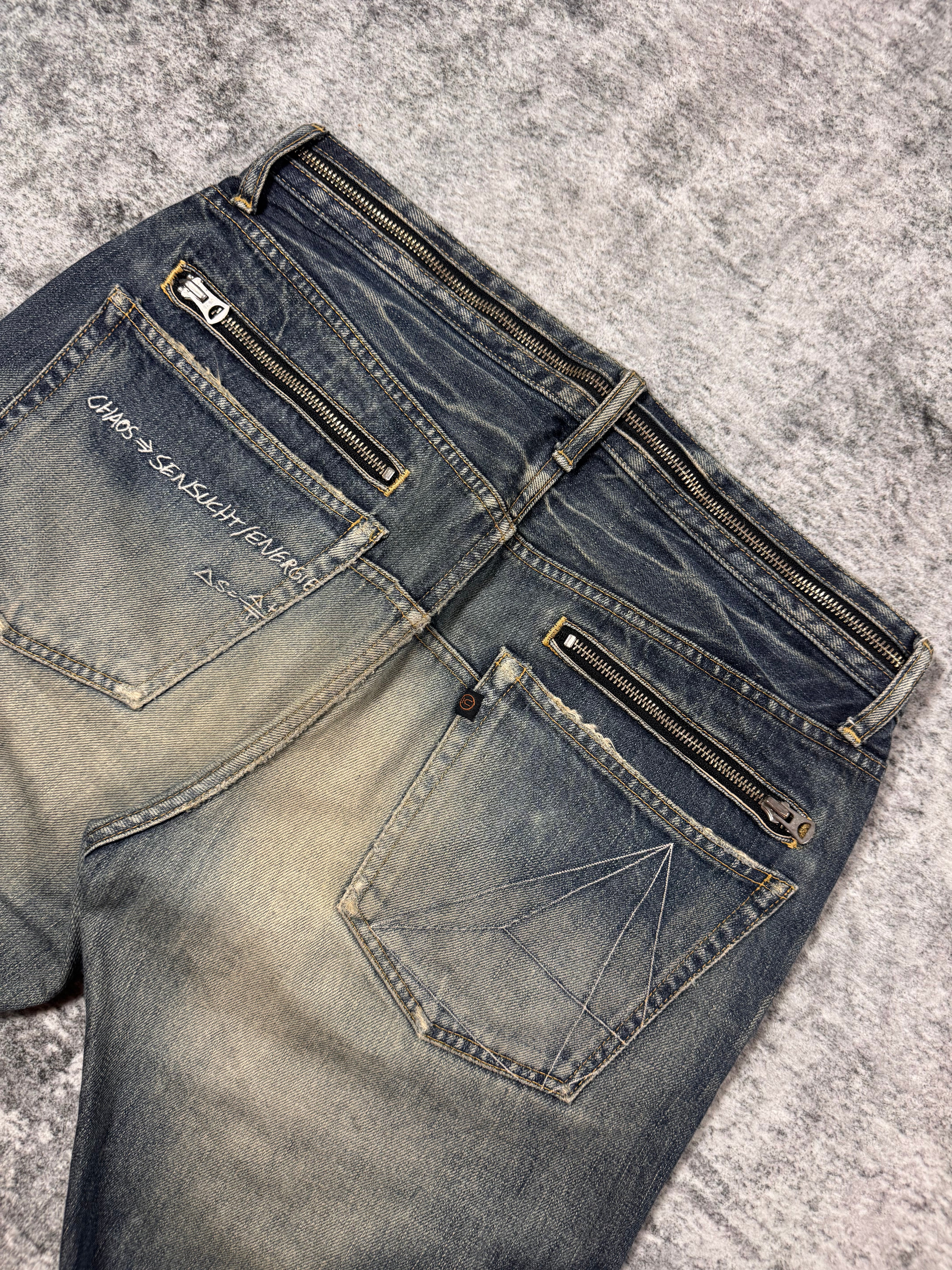 Back waist detail showing multiple zippers and geometric pocket stitching on Undercover Chaos denim